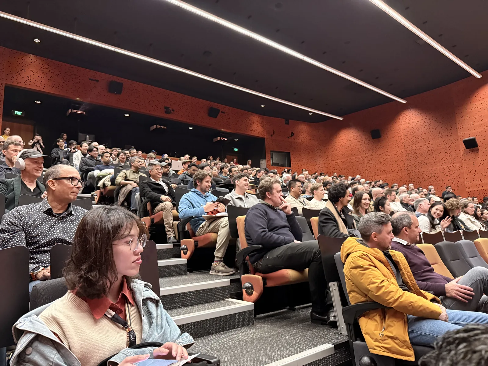 A packed lecture theatre at AUT, rows of people turned towards the stage for a community meetup.